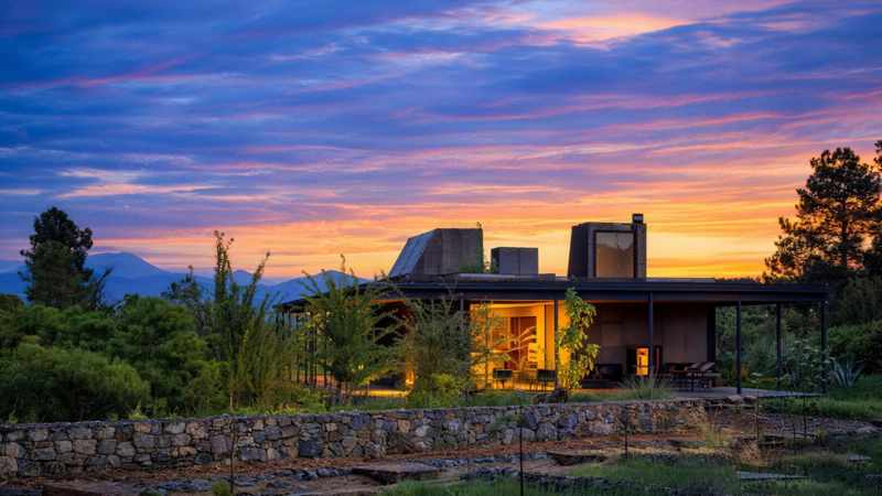 Sustainable off-grid prefabricated home in Mexico at sunset, equipped with solar power and rainwater treatment systems, eco-friendly modular house